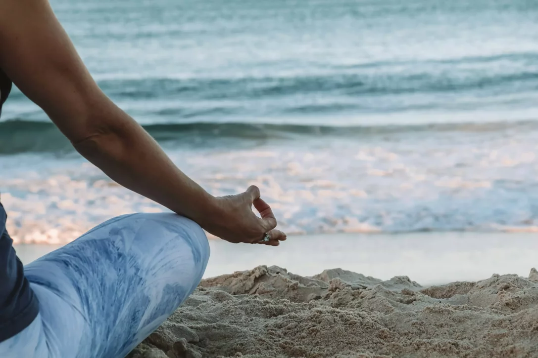 Una persona pratica yoga e meditazione sulla spiaggia di Sestri Levante, seduta sulla sabbia davanti al mare calmo