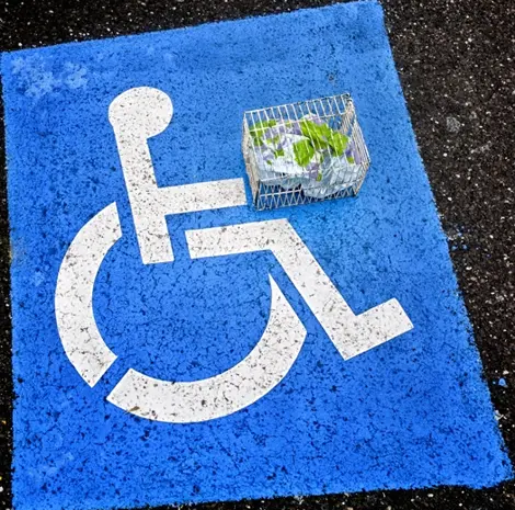 a disabled parking sign, photographed on the tarmac alongside a tiny world in a cage a disabled parking sign, photographed on the tarmac alongside a tiny world in a cage
