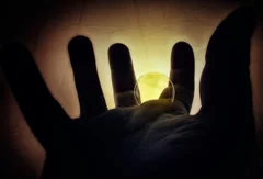 a soap bubble photographed against the light, a spherical bubble held in an open hand,