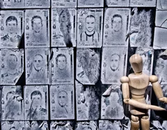 a wooden mannequin with many faces in the background, photographed,