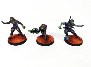 Three Nomad faction miniatures painted with iridescent purple armor and vibrant green OSL on desert bases. Three Nomad faction miniatures painted with iridescent purple armor and vibrant green OSL on desert bases.