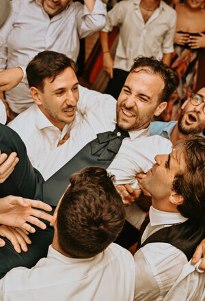 Lo sposo viene sollevato dagli amici durante la festa di matrimonio
