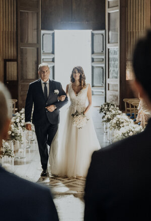 La sposa percorre la navata al braccio di un accompagnatore tra gli invitati alla cerimonia
