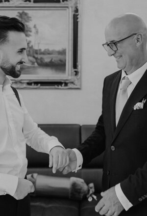 Lo sposo riceve aiuto per sistemare il polsino durante i preparativi del matrimonio