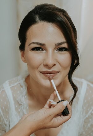 Applicazione del rossetto alla sposa durante il trucco per il matrimonio