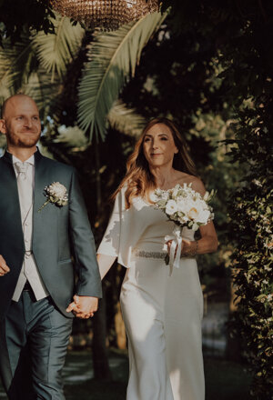 Sposi camminano mano nella mano nel verde durante il matrimonio