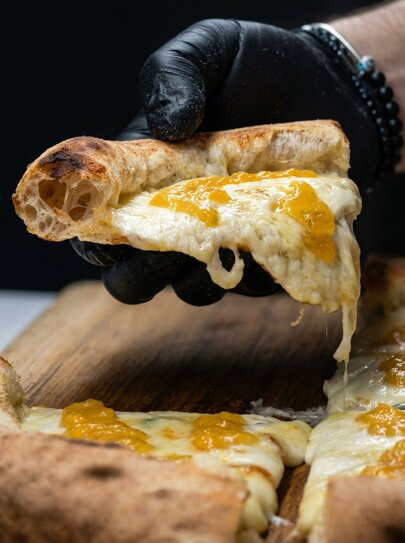 hand_holding_cheesy_pizza_slice_202606300951_2.jpeg