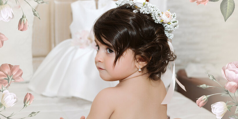 Dolce bambina nel giorno del suo battesimo, con un'acconciatura floreale, ritratta di spalle con il profilo del viso e il vestitino del battesimo sullo sfondo