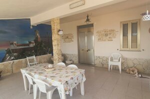 Patio coperto con tavolo, sedie bianche e murales marino al tramonto, Villetta Marisella a Pachino