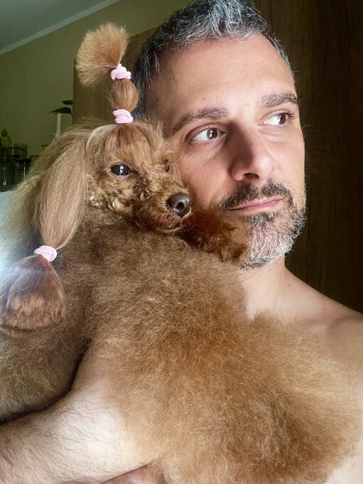 allevatore con barboncino fulvo che osservano nella stessa direzione