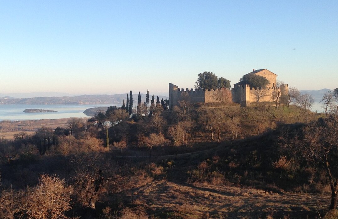 La collina di monte Gualandro, il castello omonimo arroccato sulla collina e lo sfondo del lago trasimeno con l'isola maggiore
