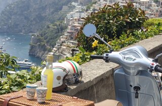 Vespa parcheggiata con vista sul mare della Costiera Amalfitana, su positano e limoncello
