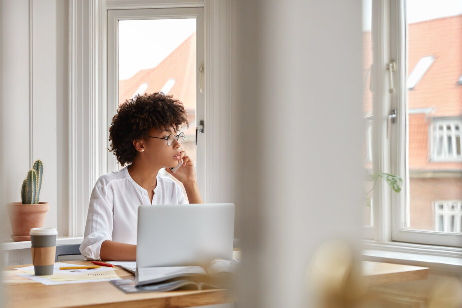 photo-of-female-entrepreneur-speaks-via-cell-phone-looks-thoughtfully-into-window-analyzes-paperwork-from-accounting-department.jpeg