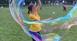 Persona che crea una grande bolla di sapone in un parco.