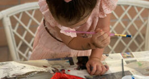 Bambina che dipinge cuori rossi durante un'attività creativa a una festa di compleanno