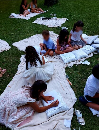 Bambini che disegnano su coperte durante un evento all'aperto, festeggiando una festa di compleanno con giochi creativi.