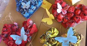 Cuori decorati con rose di carta e farfalle colorate, ideali per eventi creativi e feste di compleanno per bambini.
