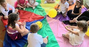 Bambini seduti in cerchio su un tappeto colorato durante un gioco creativo