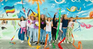 Bambini che giocano con nastri colorati davanti a un murale durante una festa di compleanno