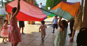 Bambini giocano sotto un telo colorato in una festa di compleanno