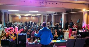 Animatore sul palco durante festa con bambini e palloncini colorati