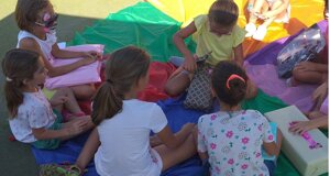 Bambini seduti in cerchio durante un party, aprendo regali. Animazione bambini, feste compleanno.