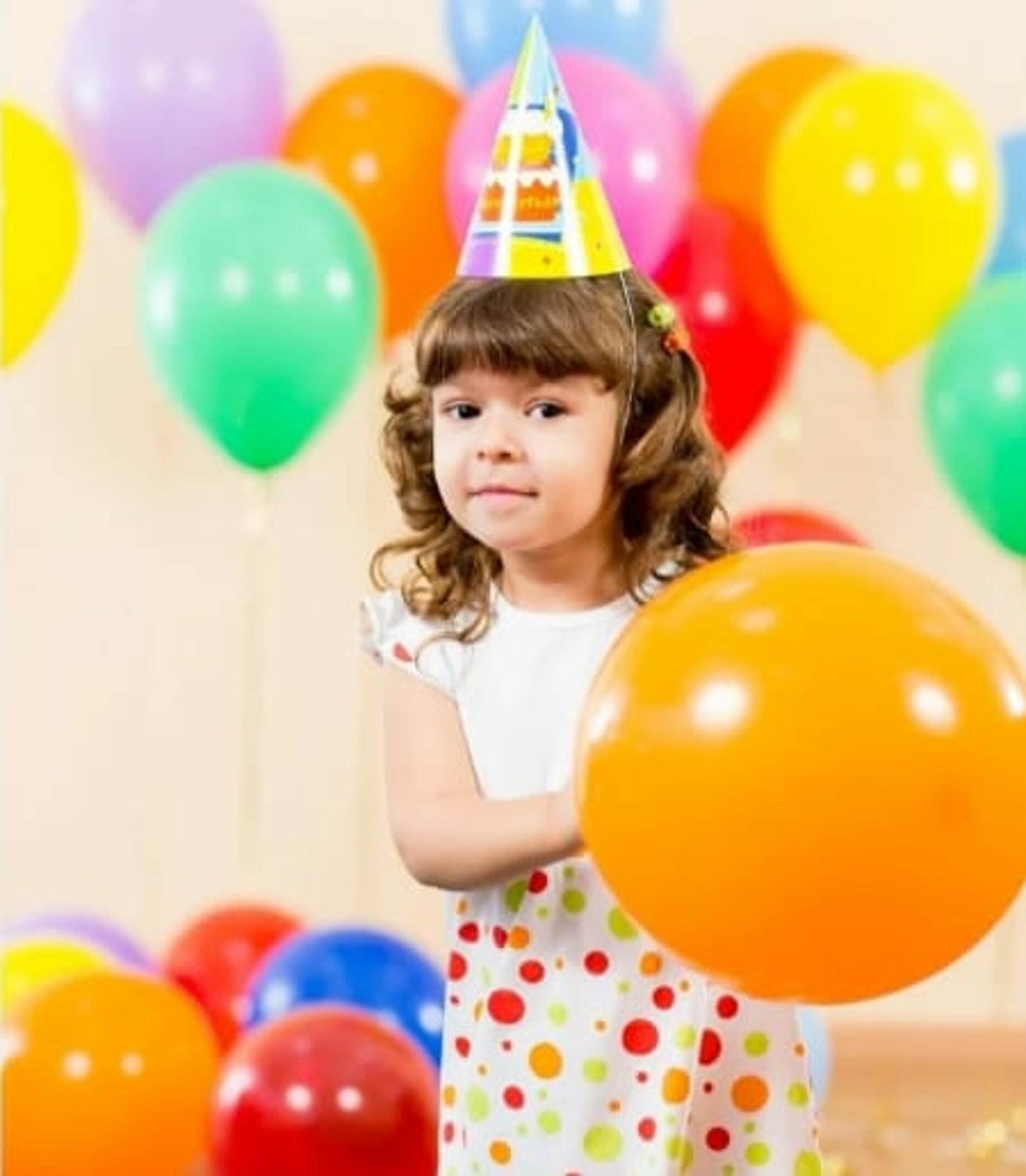 Bambina con cappellino di compleanno e palloncini colorati