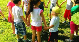 Bambini che giocano all'aperto in cerchio con un'animatrice