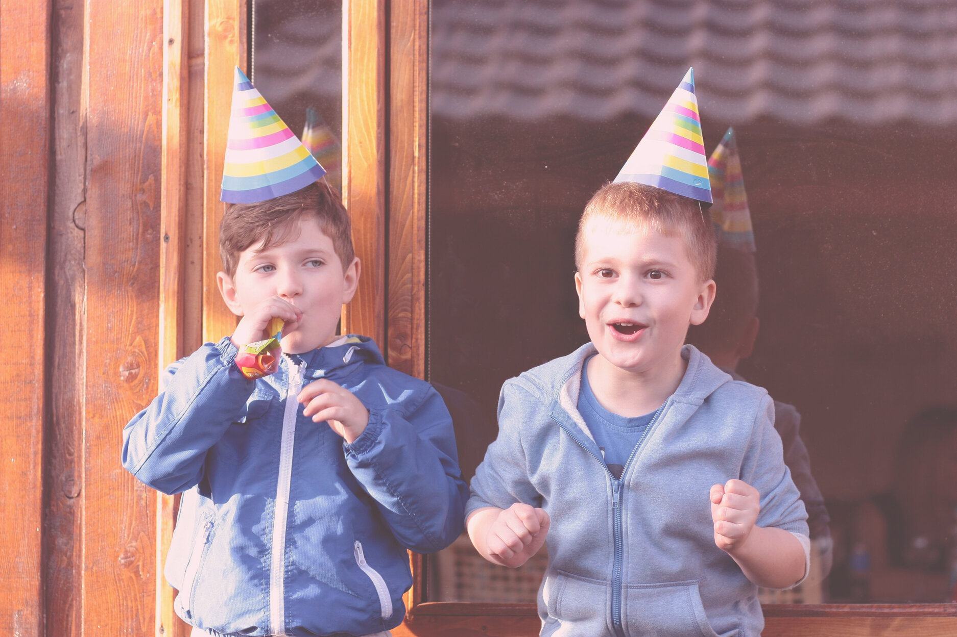 Bambini divertenti con cappelli da festa che festeggiano un compleanno all'aperto.