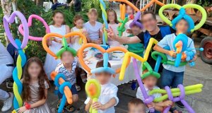 Bambini che giocano con sculture di palloncini colorati a una festa di compleanno all'aperto