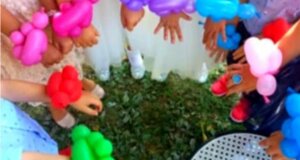 Bambini con braccialetti di palloncini colorati a una festa all'aperto.