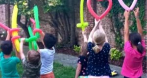Bambini che giocano con palloncini modellabili in un giardino, divertimento e creatività all'aperto