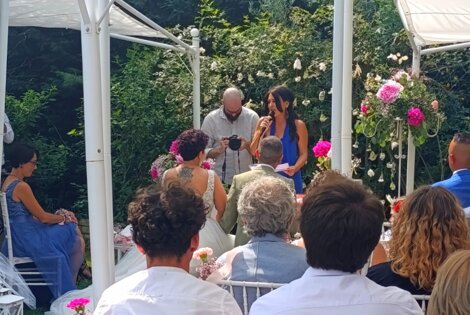 Cerimonia di matrimonio all'aperto con ospiti seduti e decorazioni floreali.