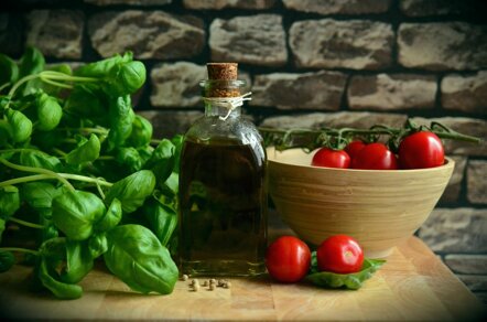 Bouteille d'huile d'olive vierge extra sicilienne avec basilic frais et tomates rouges sur pierre