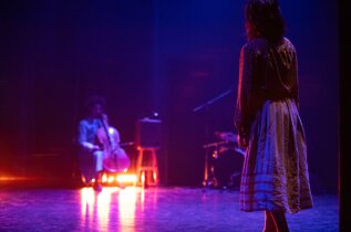 Performer standing on stage during a contemporary dance and live music performance Performer standing on stage during a contemporary dance and live music performance