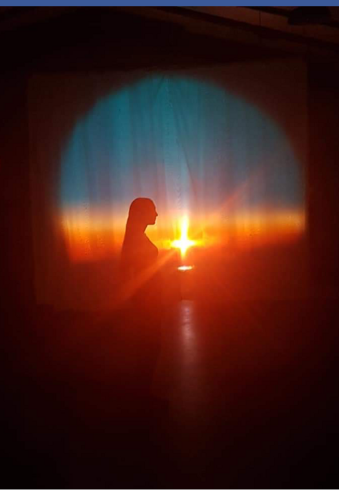 Silhouetted performer moving in front of a warm sunset projection Silhouetted performer moving in front of a warm sunset projection