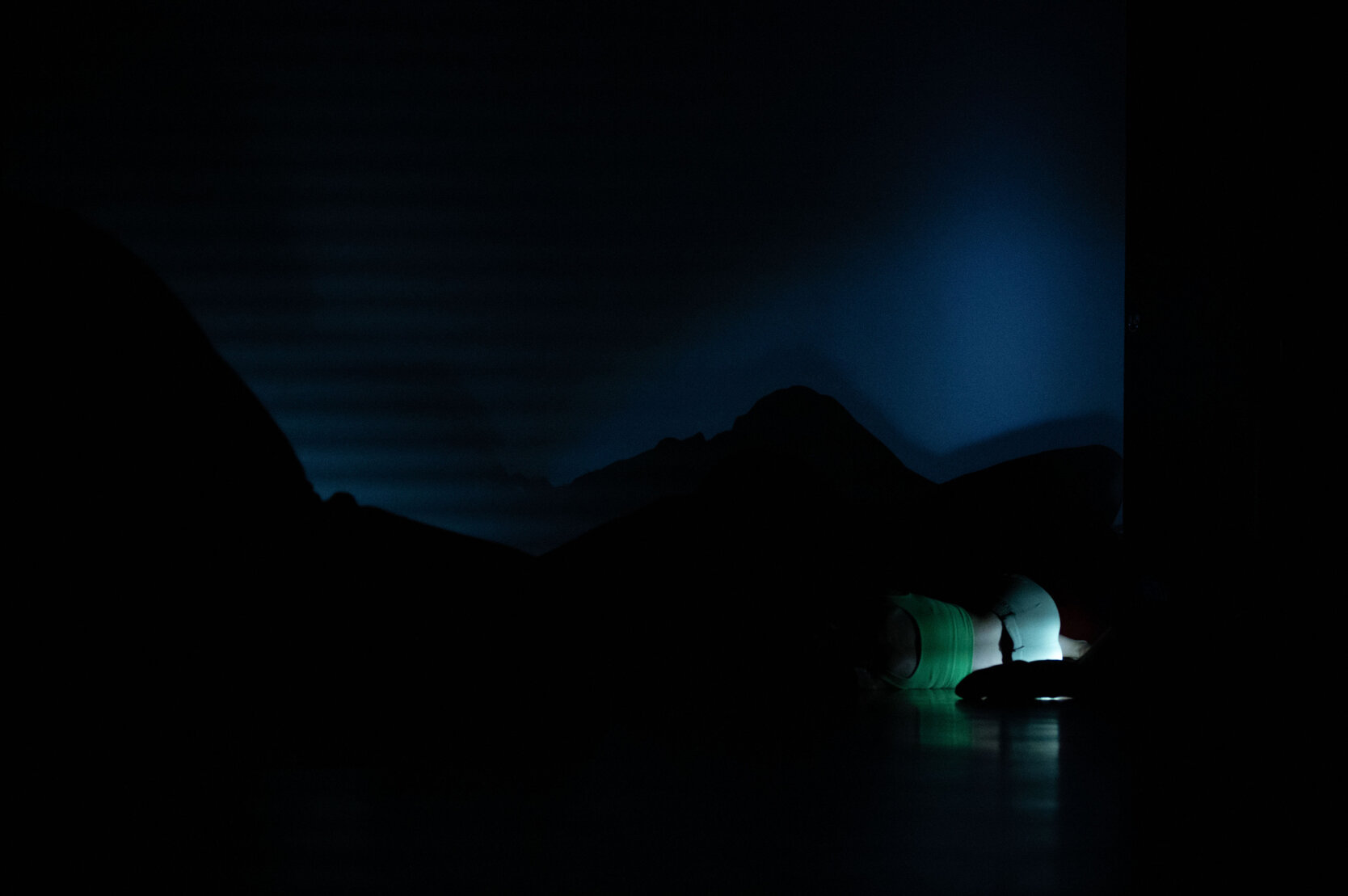 Low-lit stage scene with a dancer moving close to the floor Low-lit stage scene with a dancer moving close to the floor