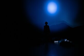 Performer silhouetted on stage under blue theatrical lighting