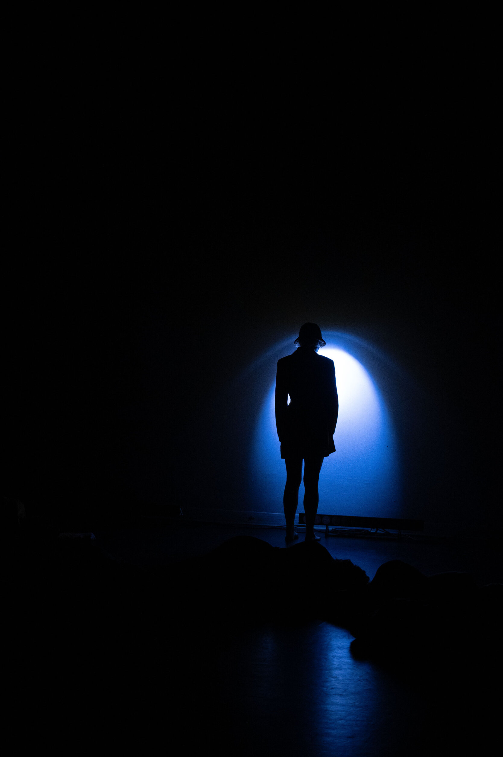 Silhouetted performer standing in a blue theatrical spotlight Silhouetted performer standing in a blue theatrical spotlight