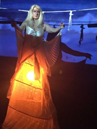 Performer moving with warm light and blue stage projection