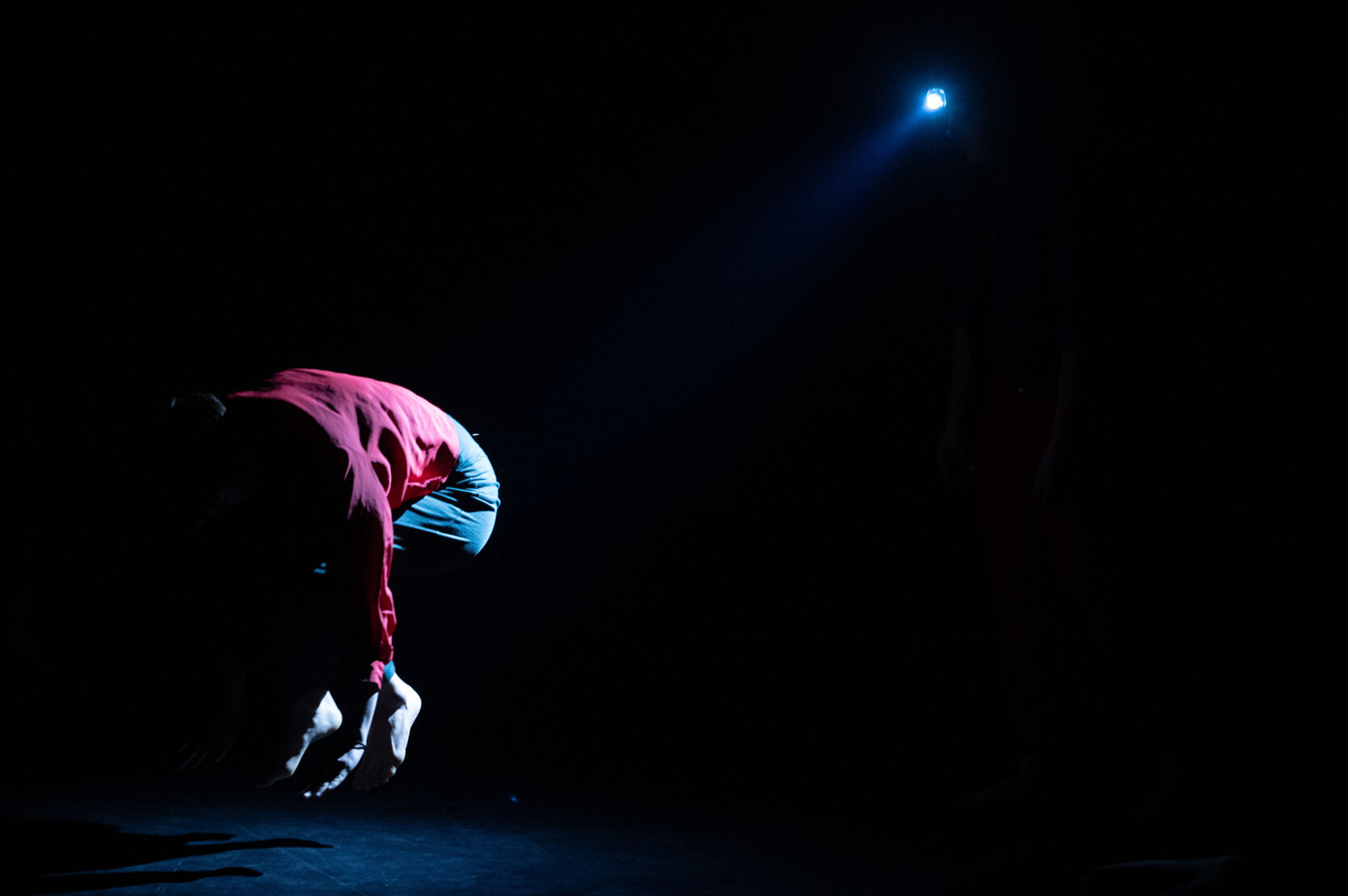 Dancer performing in low stage light during a contemporary dance project