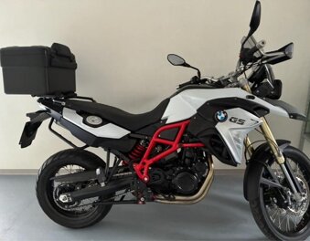 Adventure motorcycle parked in a courtyard with stone pillars.