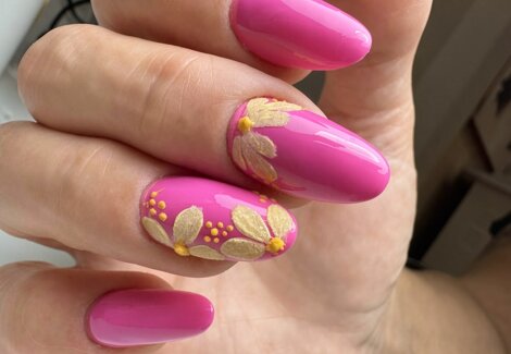 mano femminile dopo manicure dell'estetista, smalto rosa con decorazioni nail art gialle in rilievo