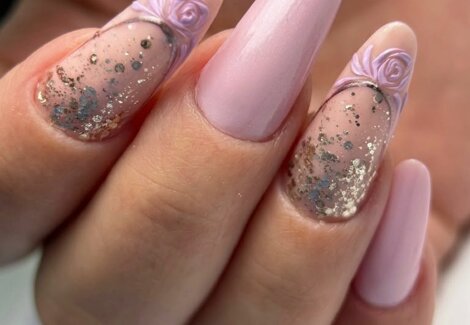 Dopo la manicure dell'estetista, mano femminile con smalto gel semipermanente trasparente e rosa e decorazioni oro nail art
