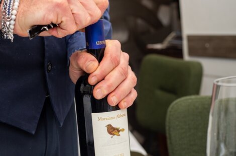 il direttore di sala apre una bottiglia di vino piemontese