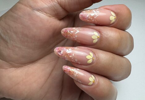 semipermanente gel e nail art dopo la manicure dell'estetista, la mano socchiusa con decorazioni floreali e smolto trasparente