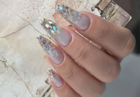 Dopo la manicure dell'estetista, mano femminile con smalto gel semipermanente trasparente e decorazioni glitter nail art