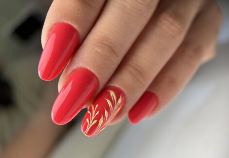 mano femminile dopo la manicure dell'estetista e ricostruzione unghie con smalto rosso e decorazione nailart