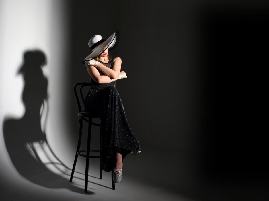 Black and white artistic fashion photo of a seated woman in a studio.