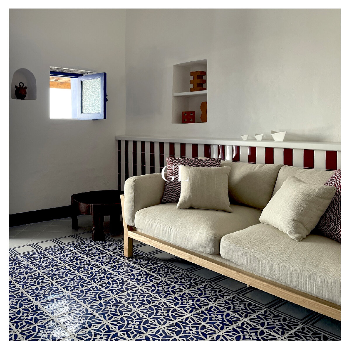 Cozy living room with beige sofa, blue Sicilian tiles, handcrafted ceramics on the wall.